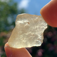 libyan desert glass is held up with sunlight shining through it