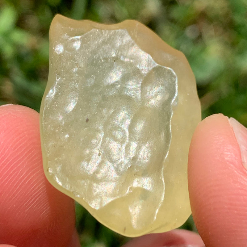 libyan desert glass is held up showing details with sunlight shining on it