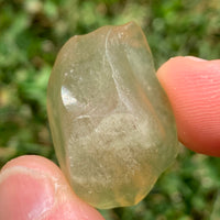 libyan desert glass is held up showing details with sunlight shining on it