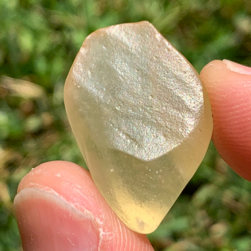 libyan desert glass is held up showing details with sunlight shining on it