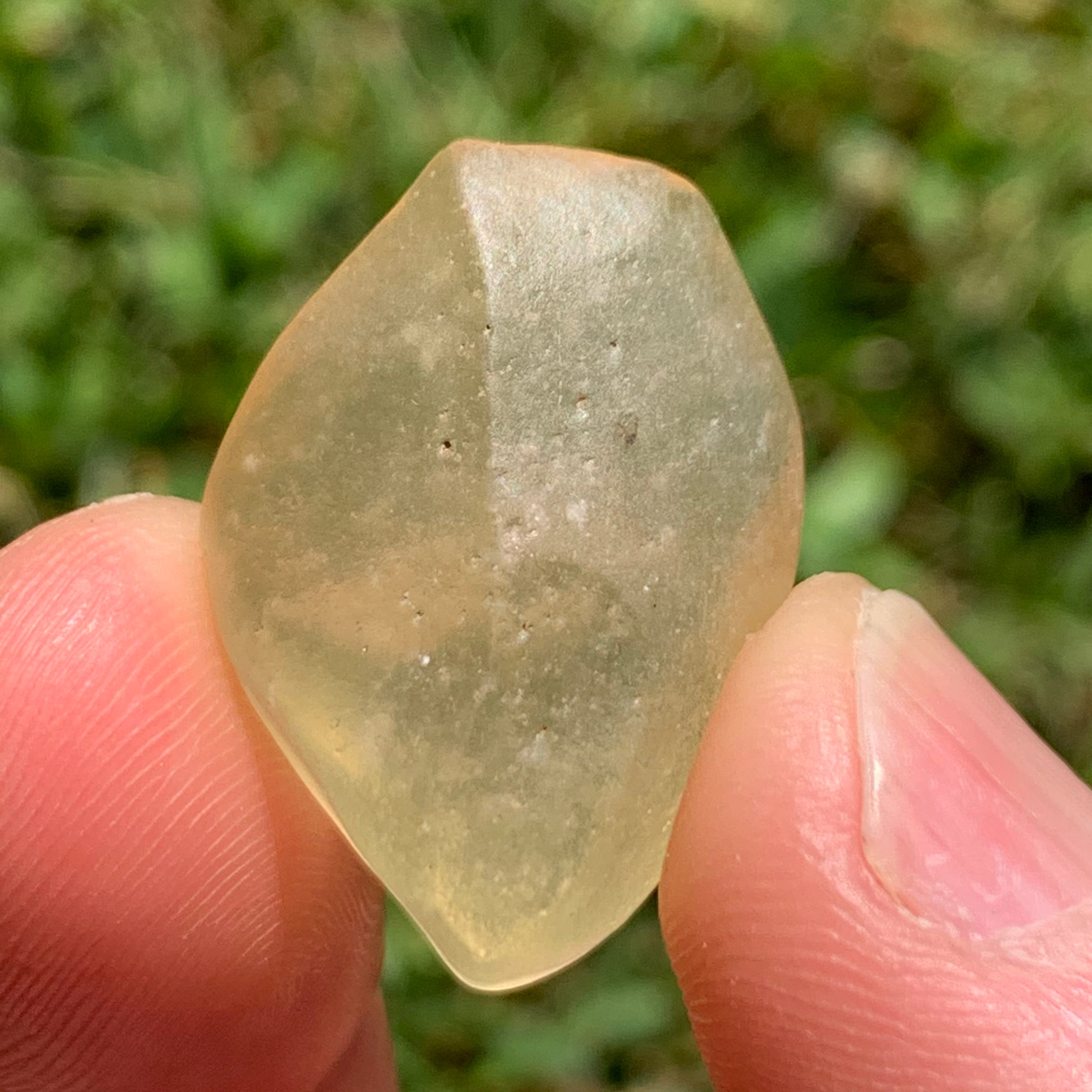 libyan desert glass is held up showing details with sunlight shining on it