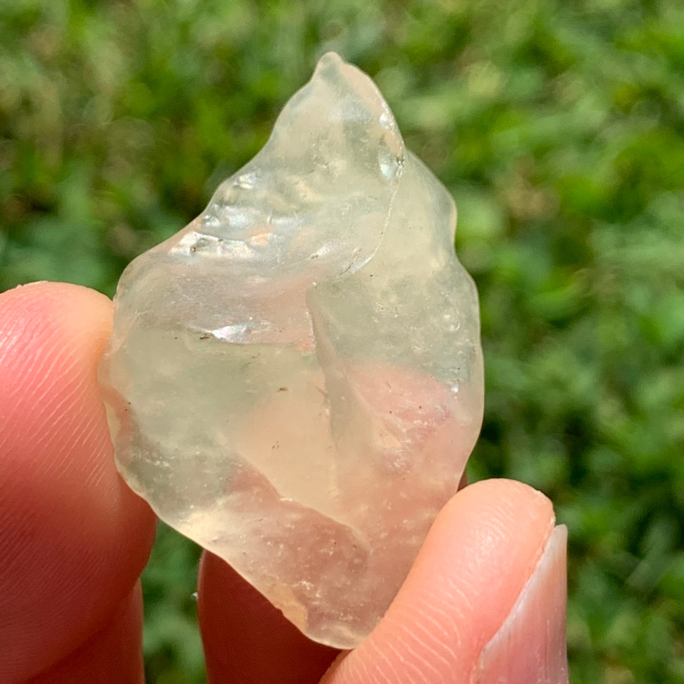 libyan desert glass is held up showing details with sunlight shining on it