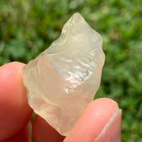 libyan desert glass is held up showing details with sunlight shining on it