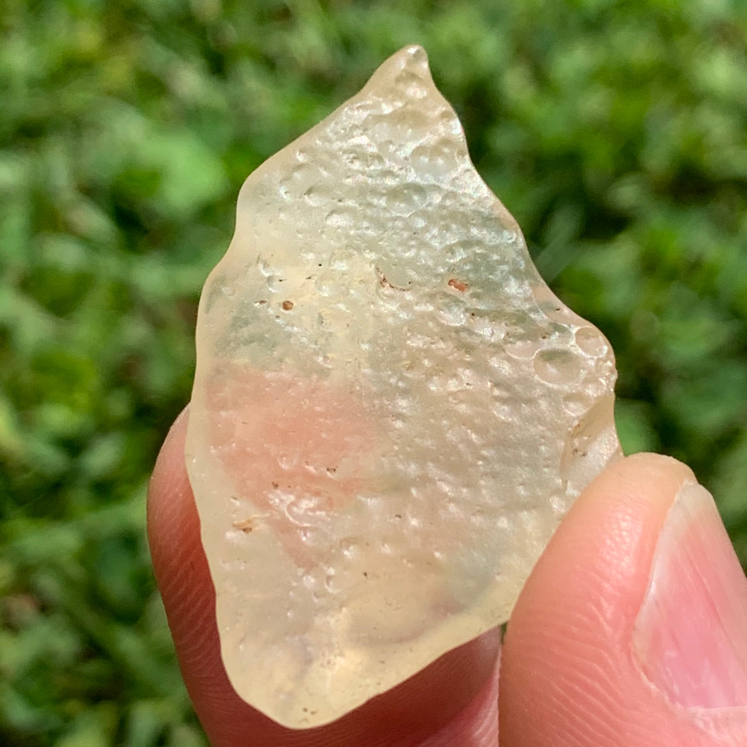 libyan desert glass is held up showing details with sunlight shining on it