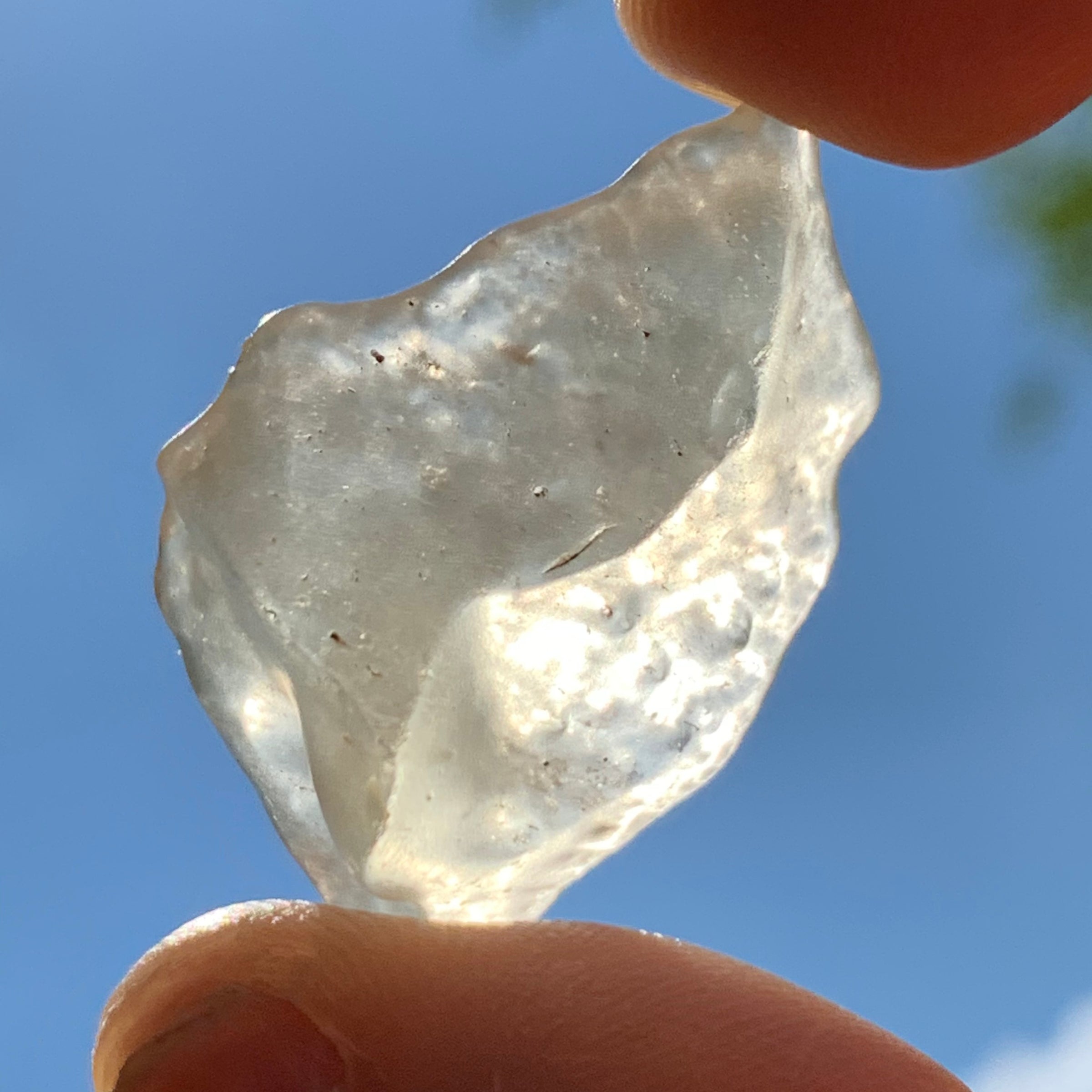 libyan desert glass is held up with sunlight shining through it