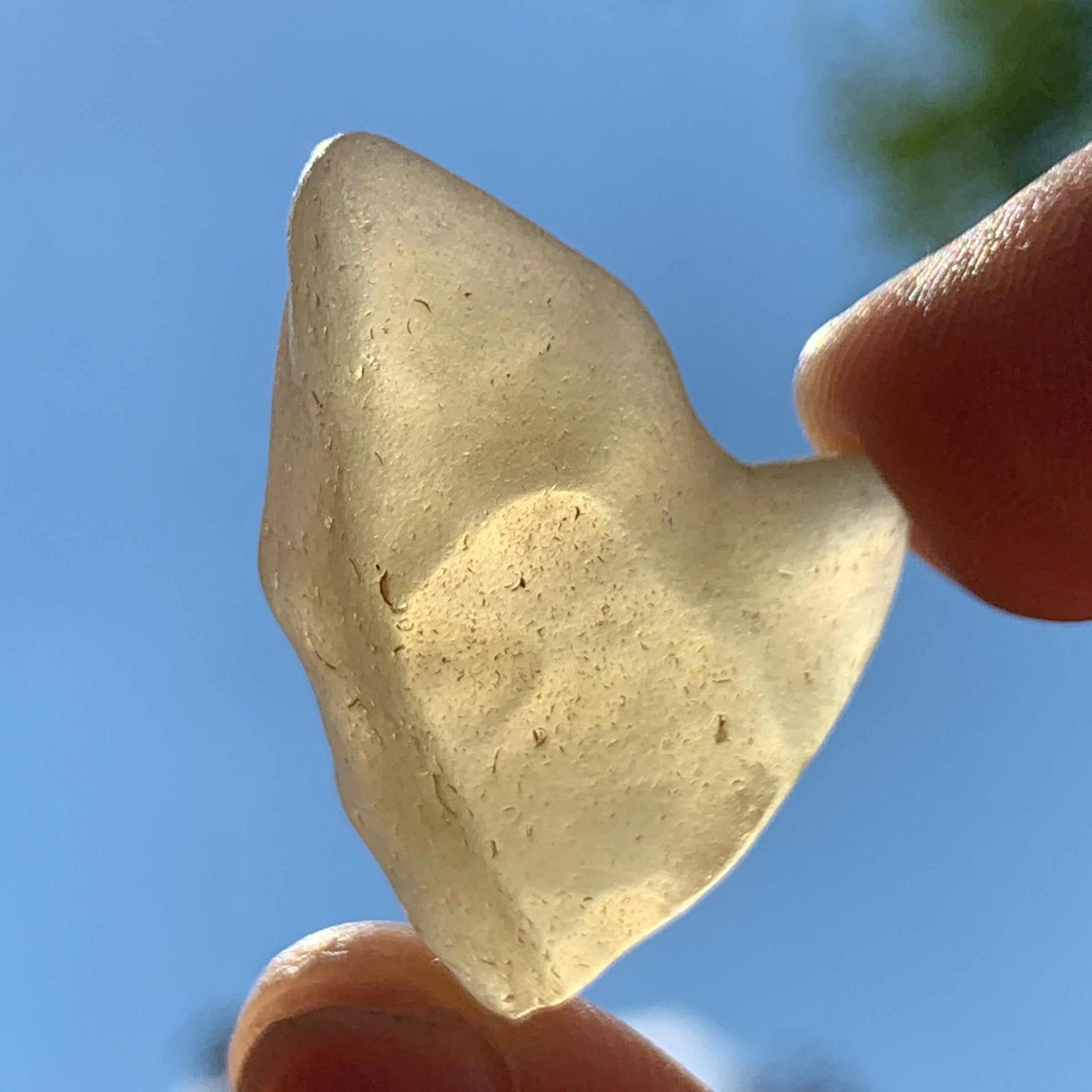 libyan desert glass is held up with sunlight shining through it