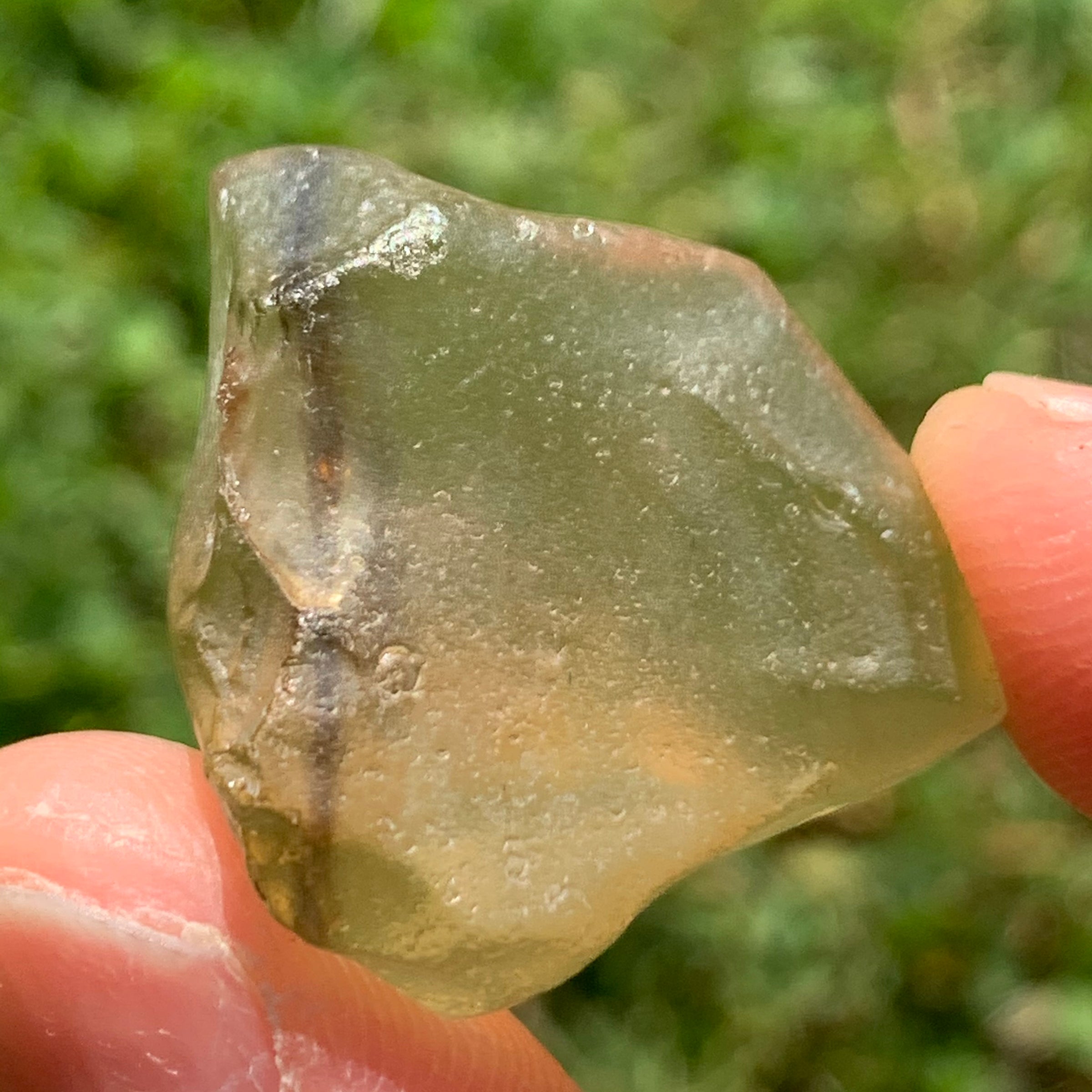 libyan desert glass is held up showing details with sunlight shining on it