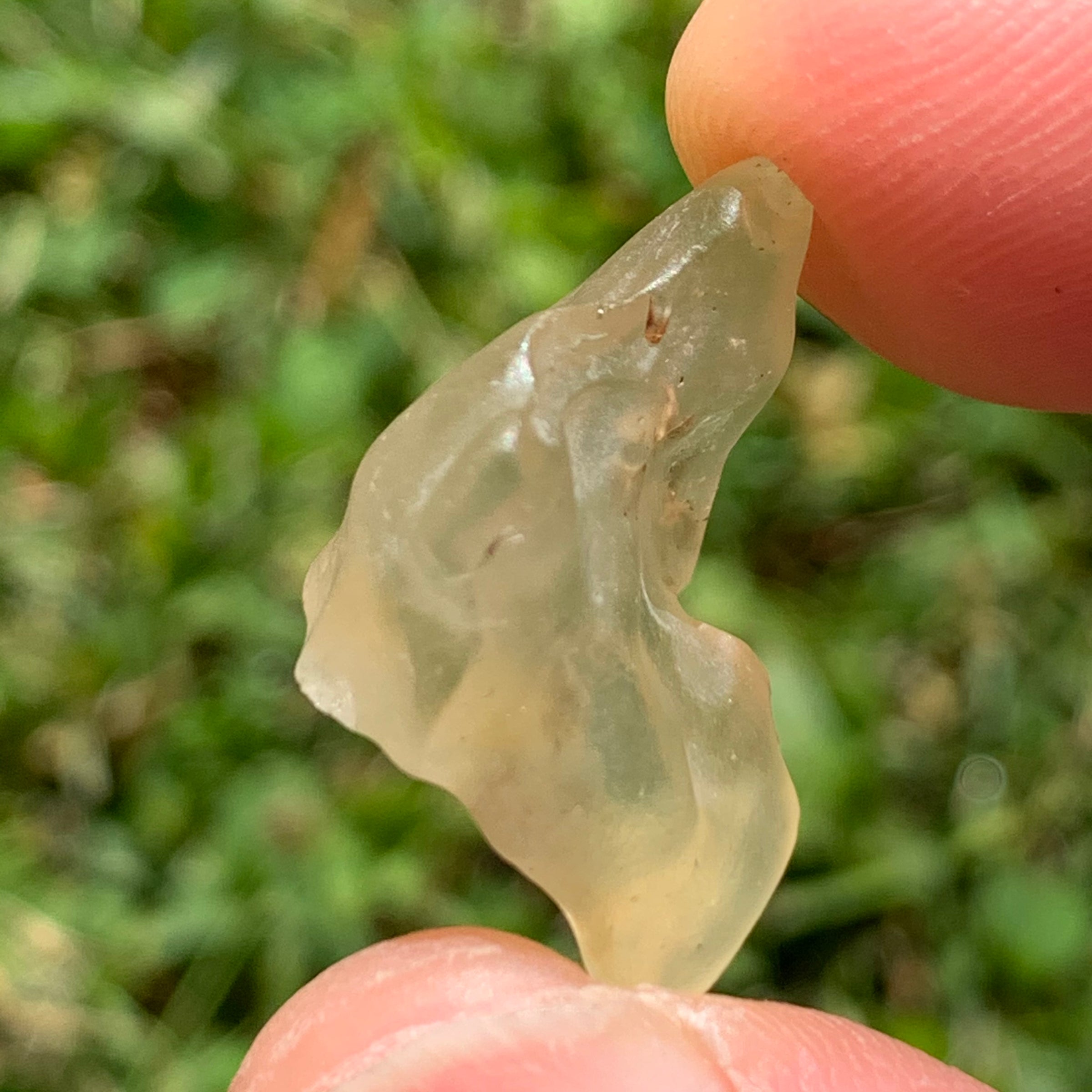 libyan desert glass is held up showing details with sunlight shining on it