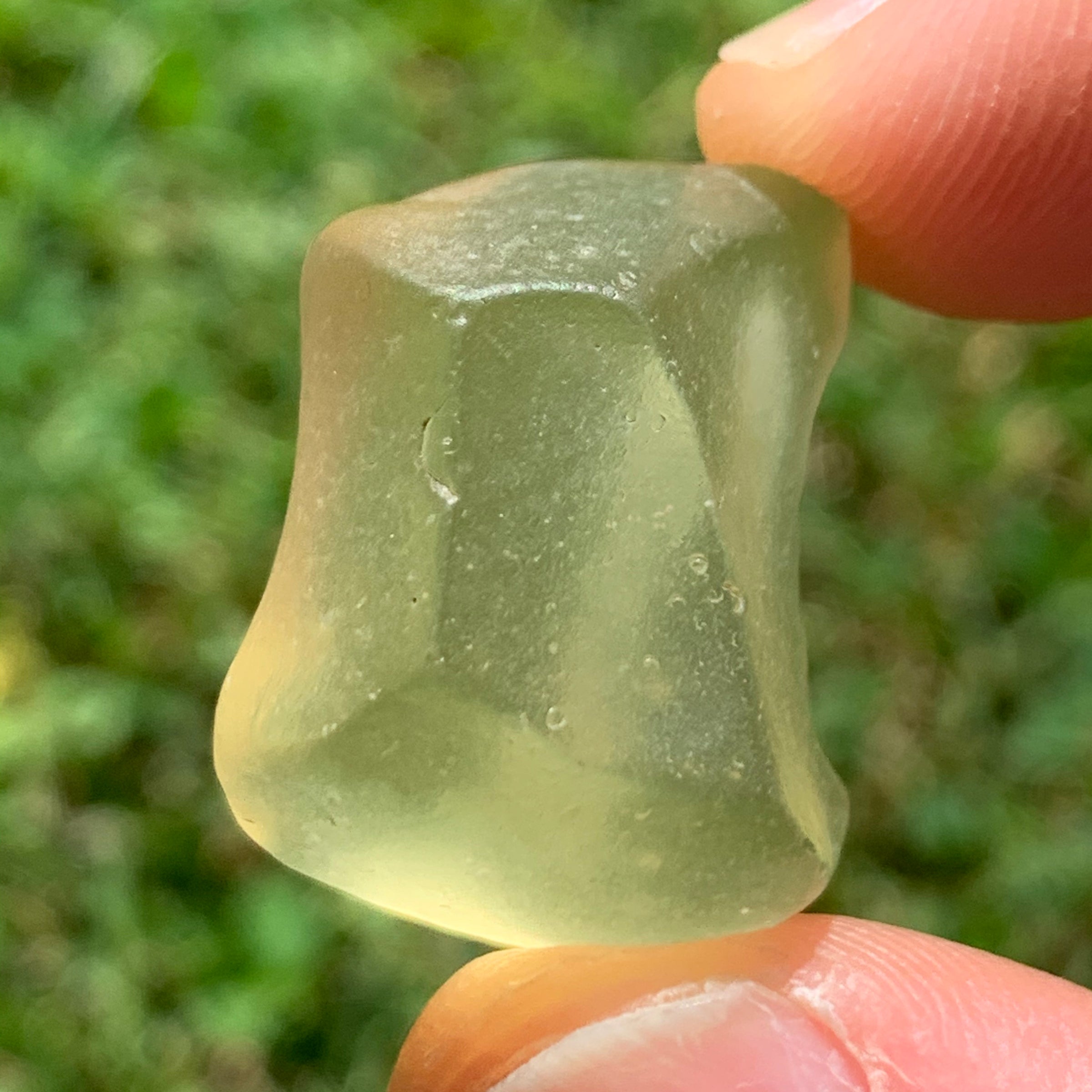 libyan desert glass is held up to show details with sunlight shining on it