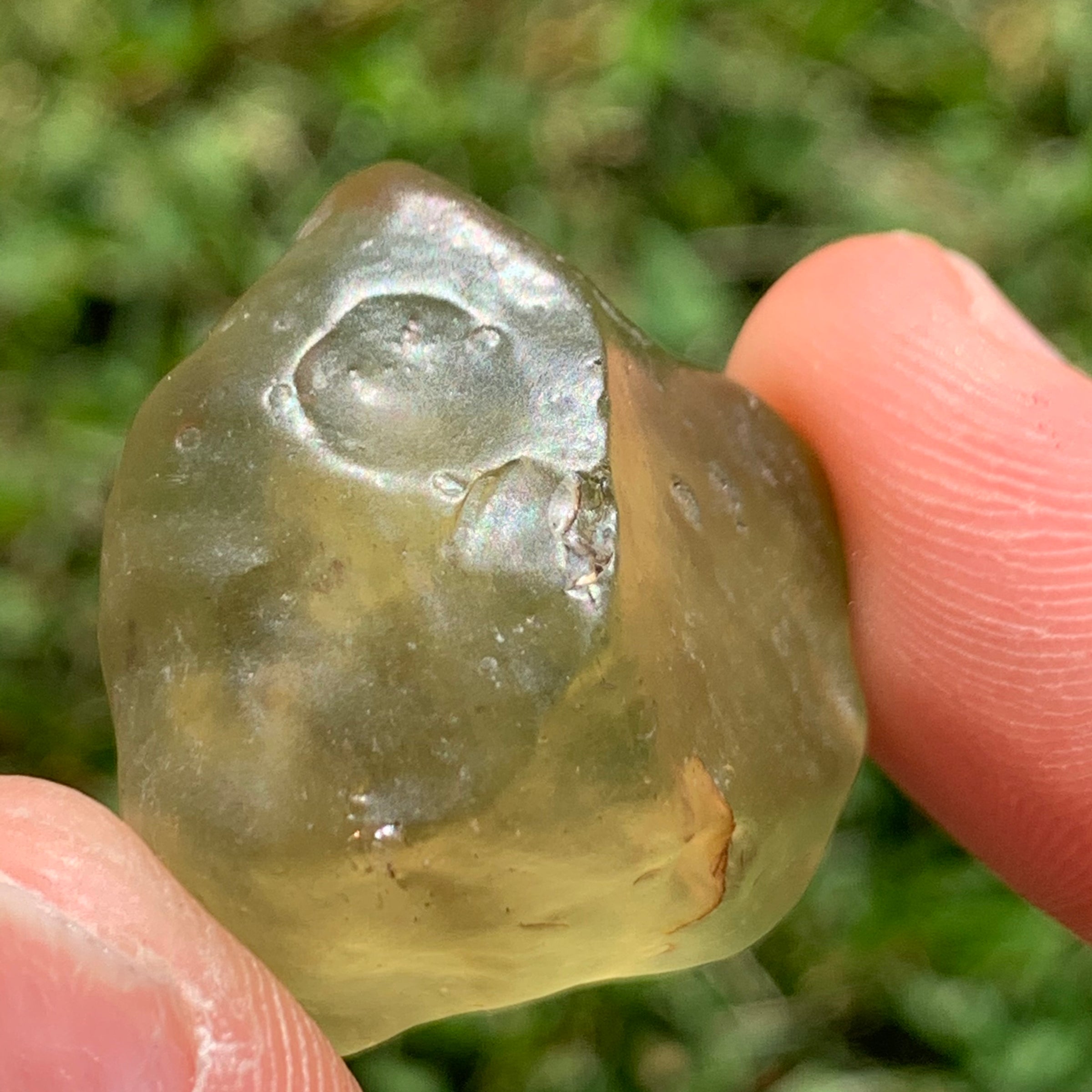 libyan desert glass is held up to show details with sunlight shining on it