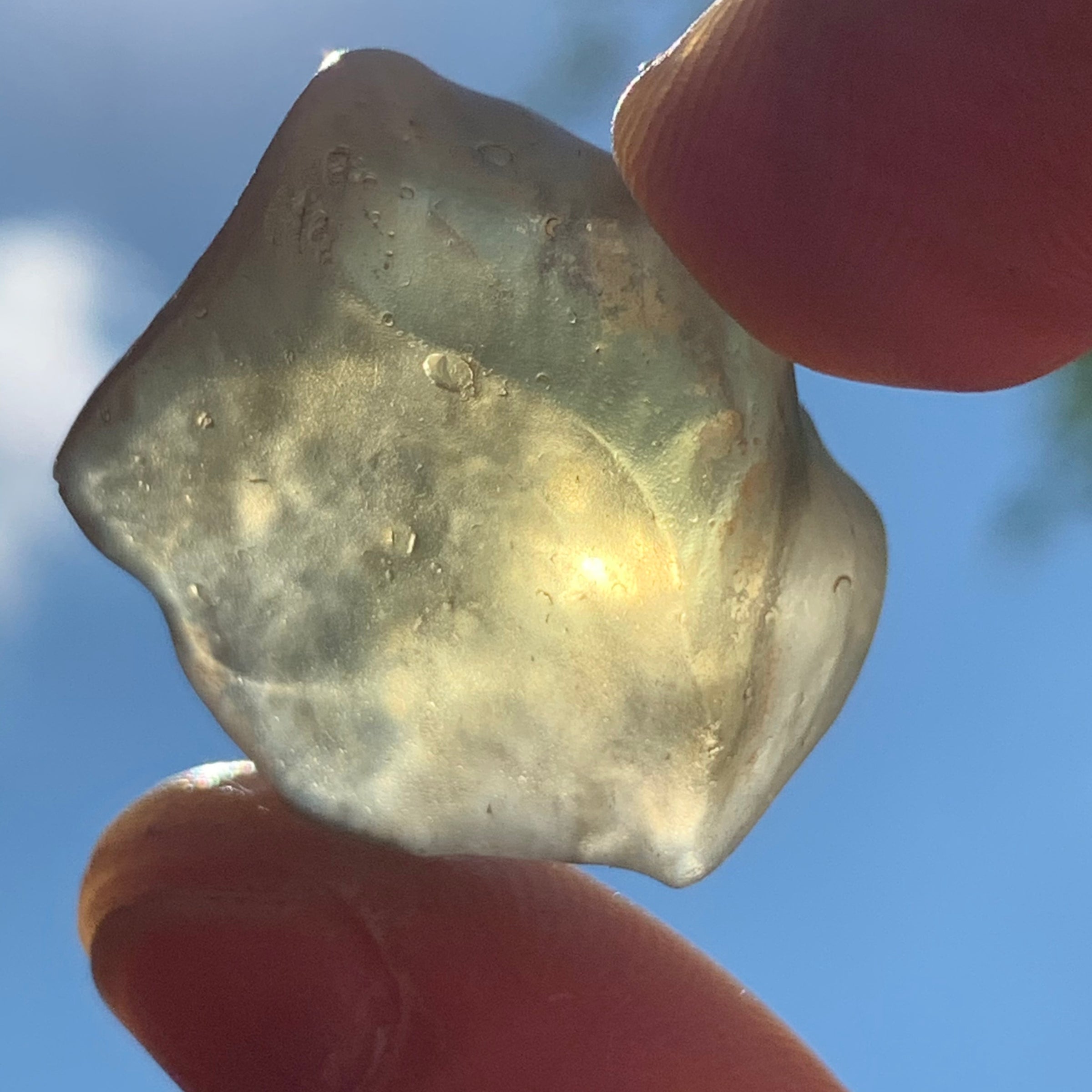 libyan desert glass is held up with sunlight shining through it