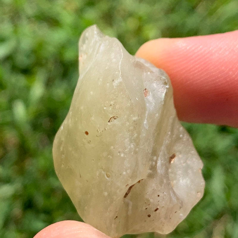 libyan desert glass is held up to show details with sunlight shining on it