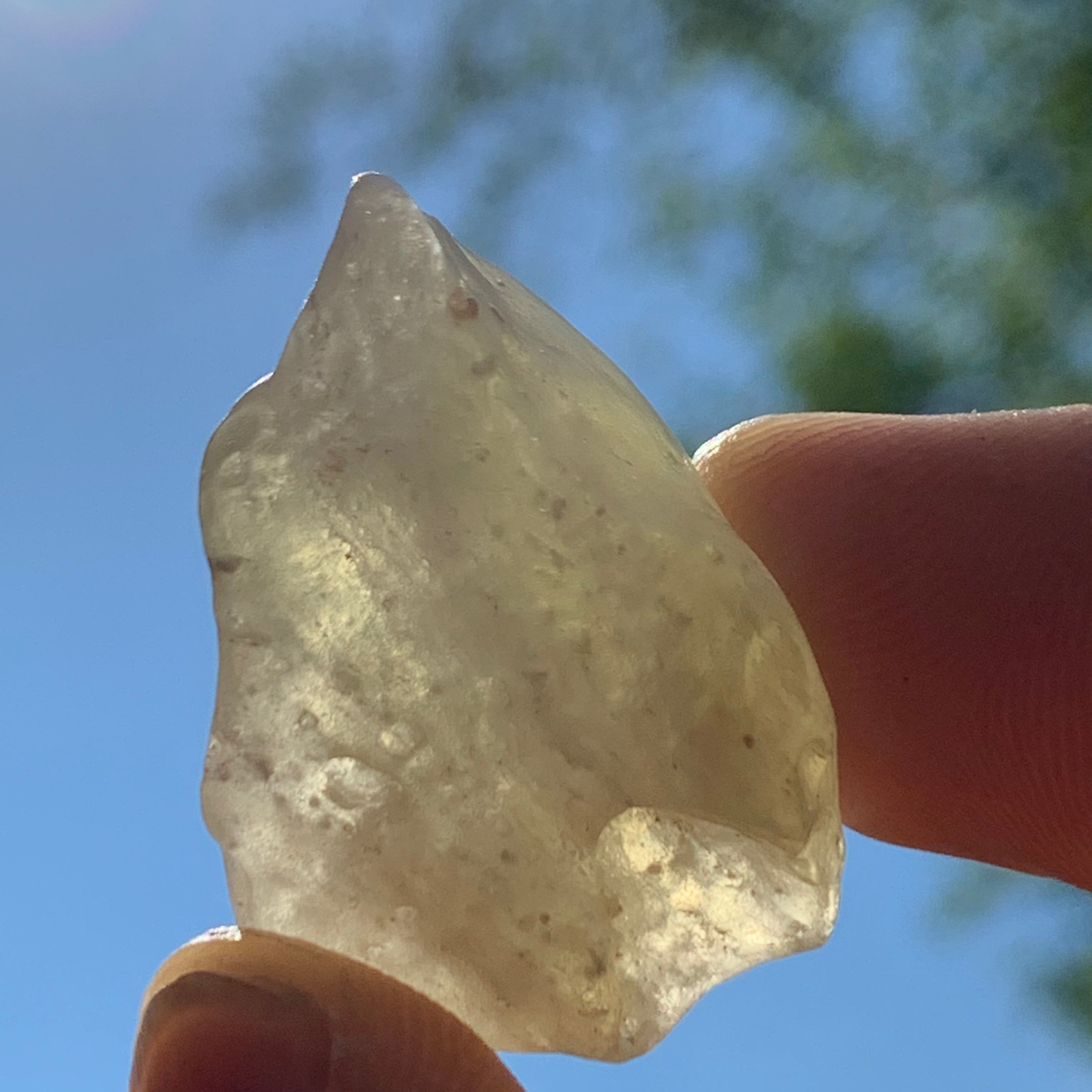 libyan desert glass is held up with sunlight shining through it