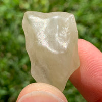 libyan desert glass is held up to show details with sunlight shining on it