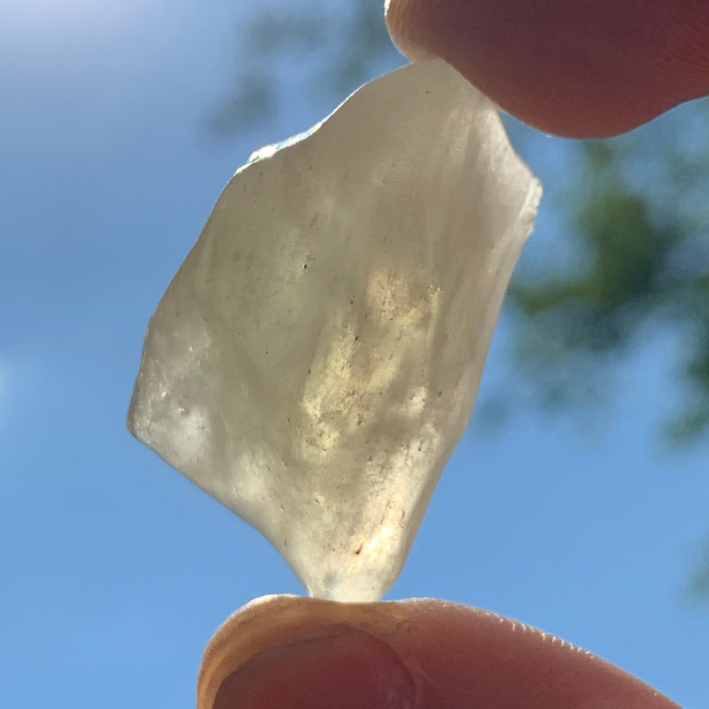 libyan desert glass is held up with sunlight shining through it