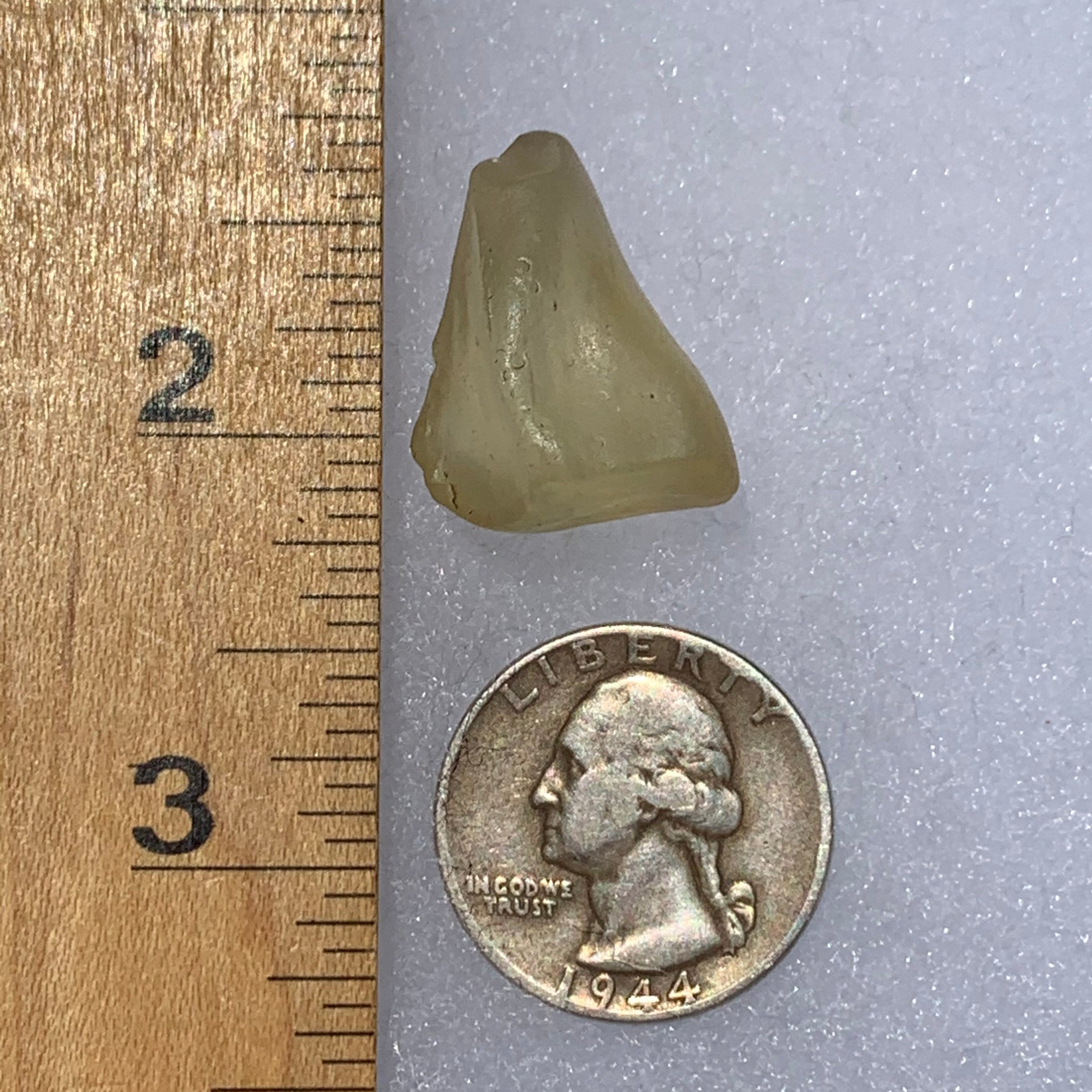 libyan desert glass next to a ruler and US quarter for scale