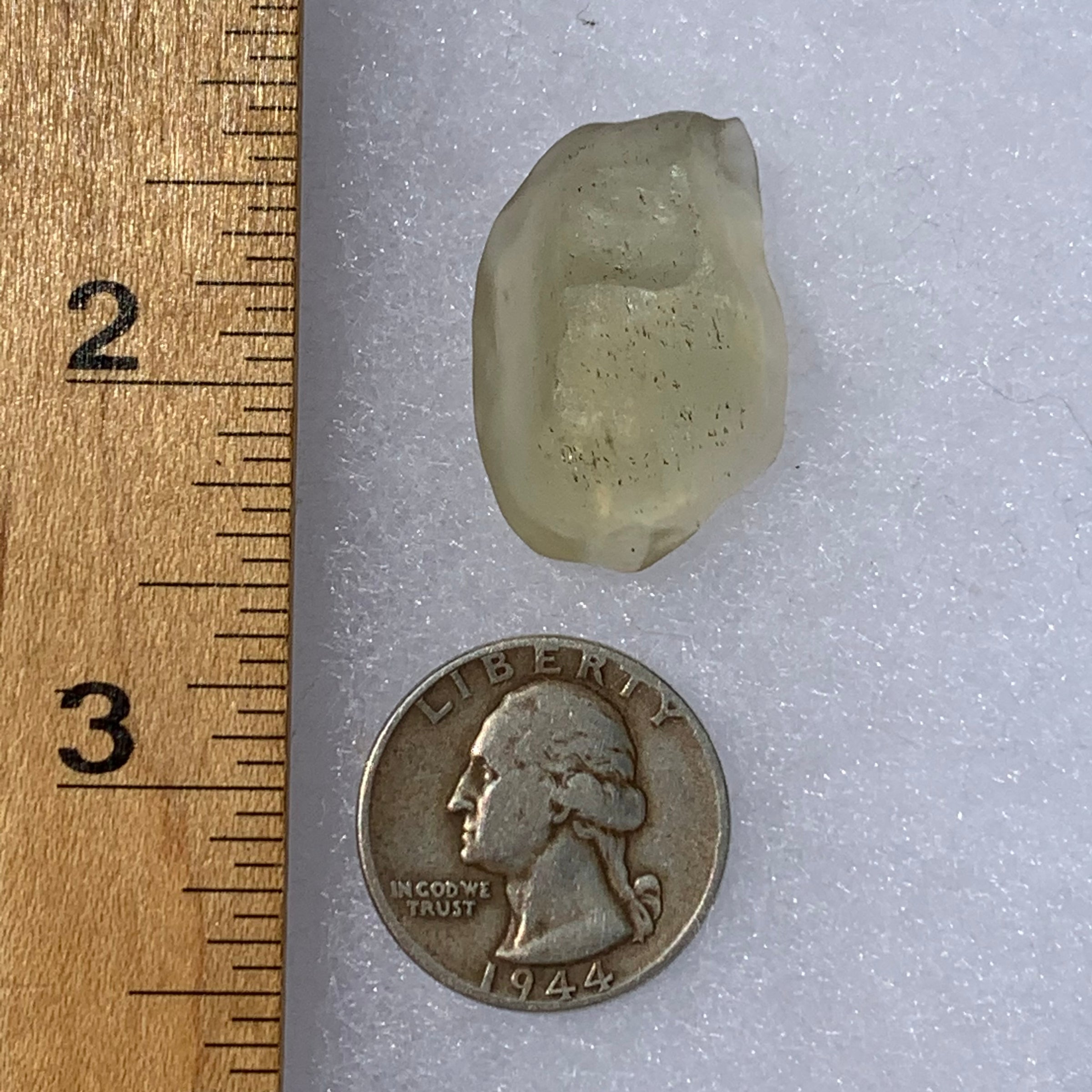 libyan desert glass next to a ruler and US quarter for scale