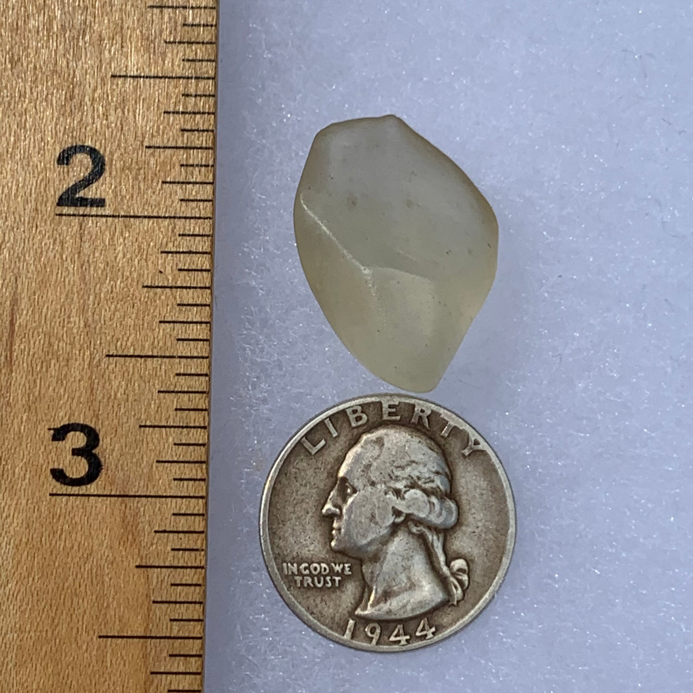 libyan desert glass next to a ruler and US quarter for scale