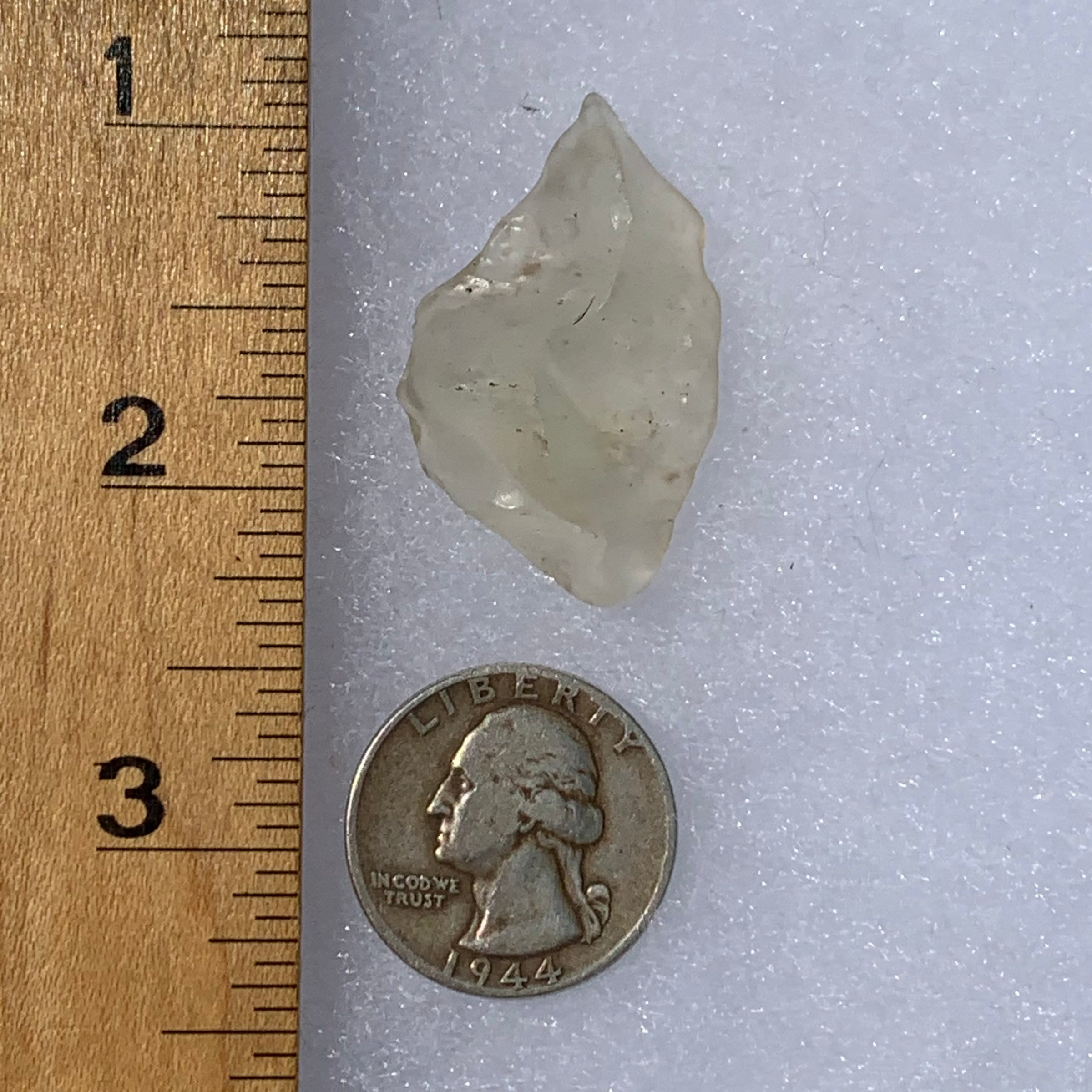 libyan desert glass next to a ruler and US quarter for scale