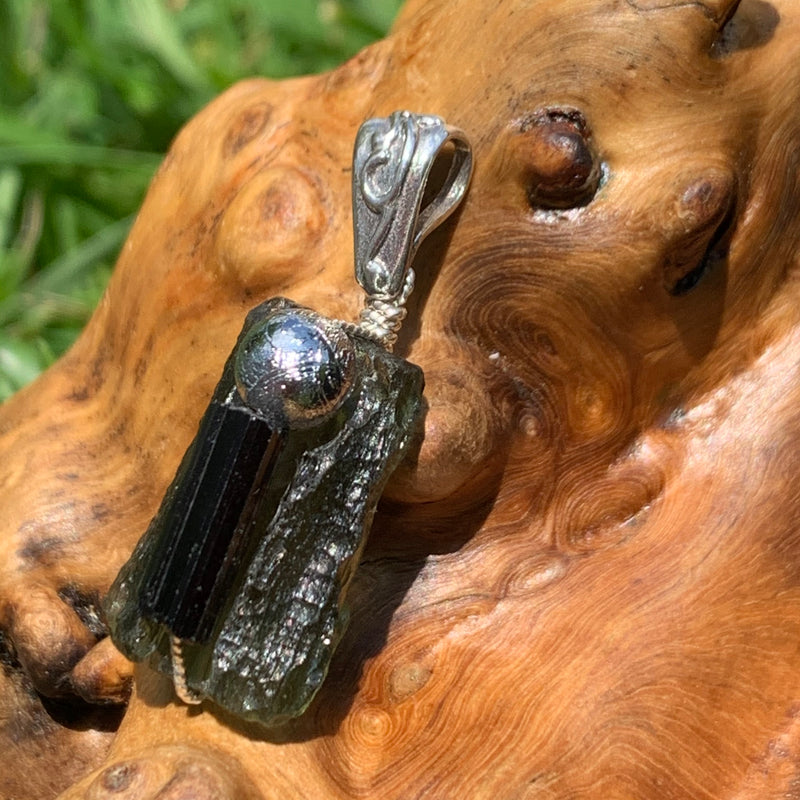 the texture of the moldavite shines in the sun and the silver bail has a swirl on it