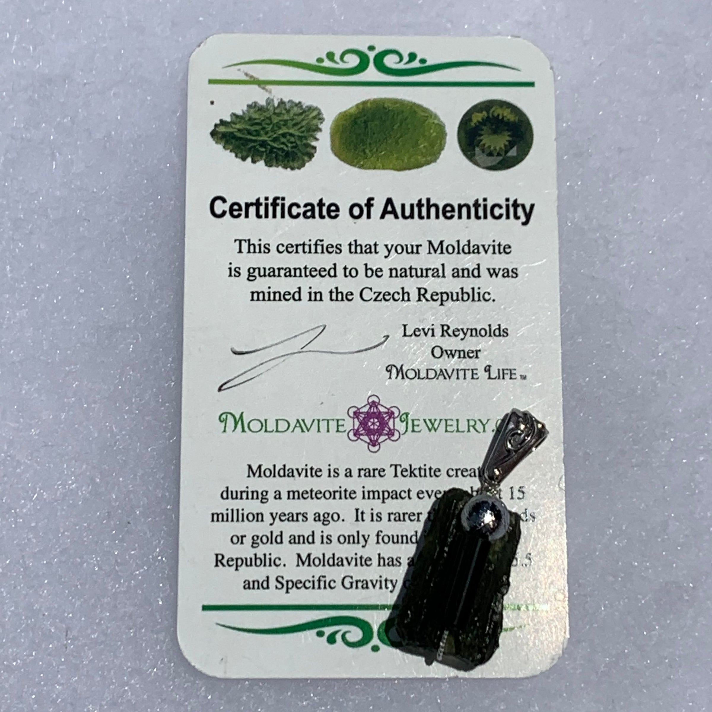the pendant sits on a moldavite life certificate of authenticity