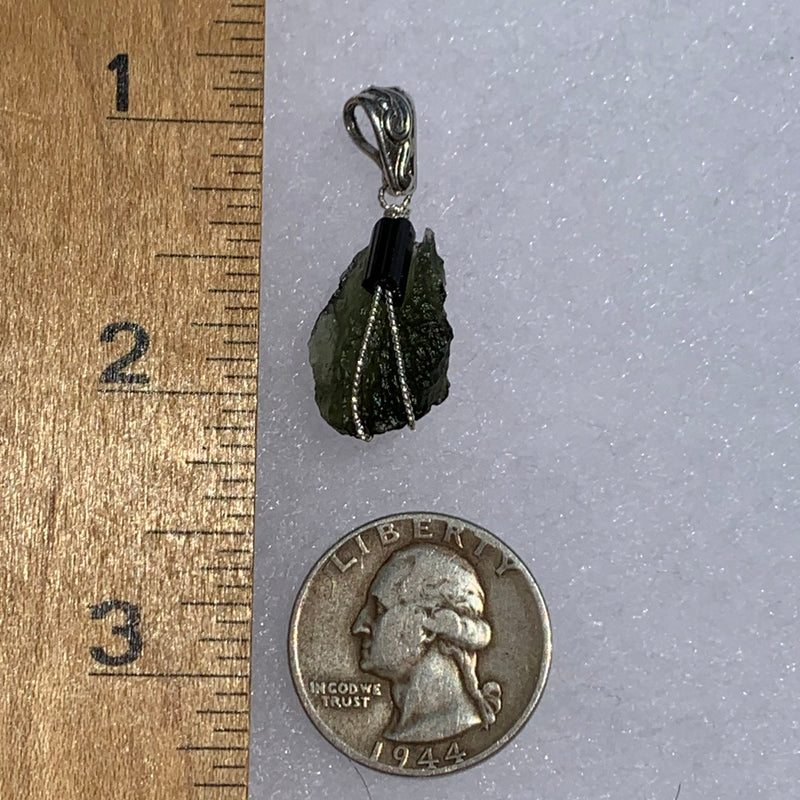 the moldavite tourmaline pendant is displayed next to a ruler and US quarter