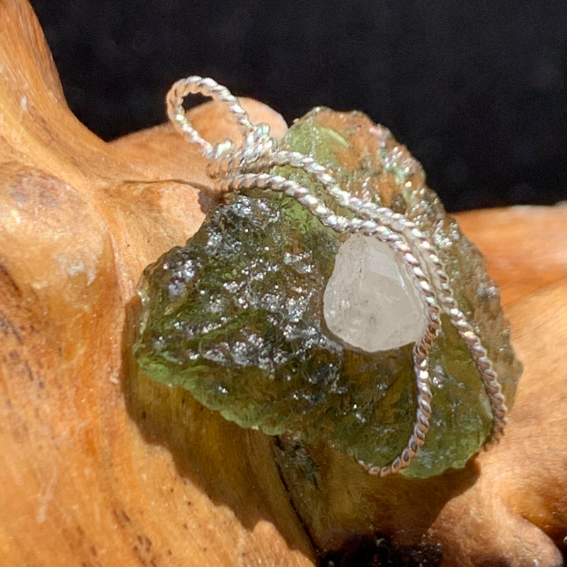 sterling silver wire wrapped raw moldavite tektite and colorado phenacite crystal pendant sitting on driftwood for display