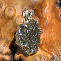 sterling silver moldavite tektite and herkimer diamond basket pendant sitting on driftwood for display