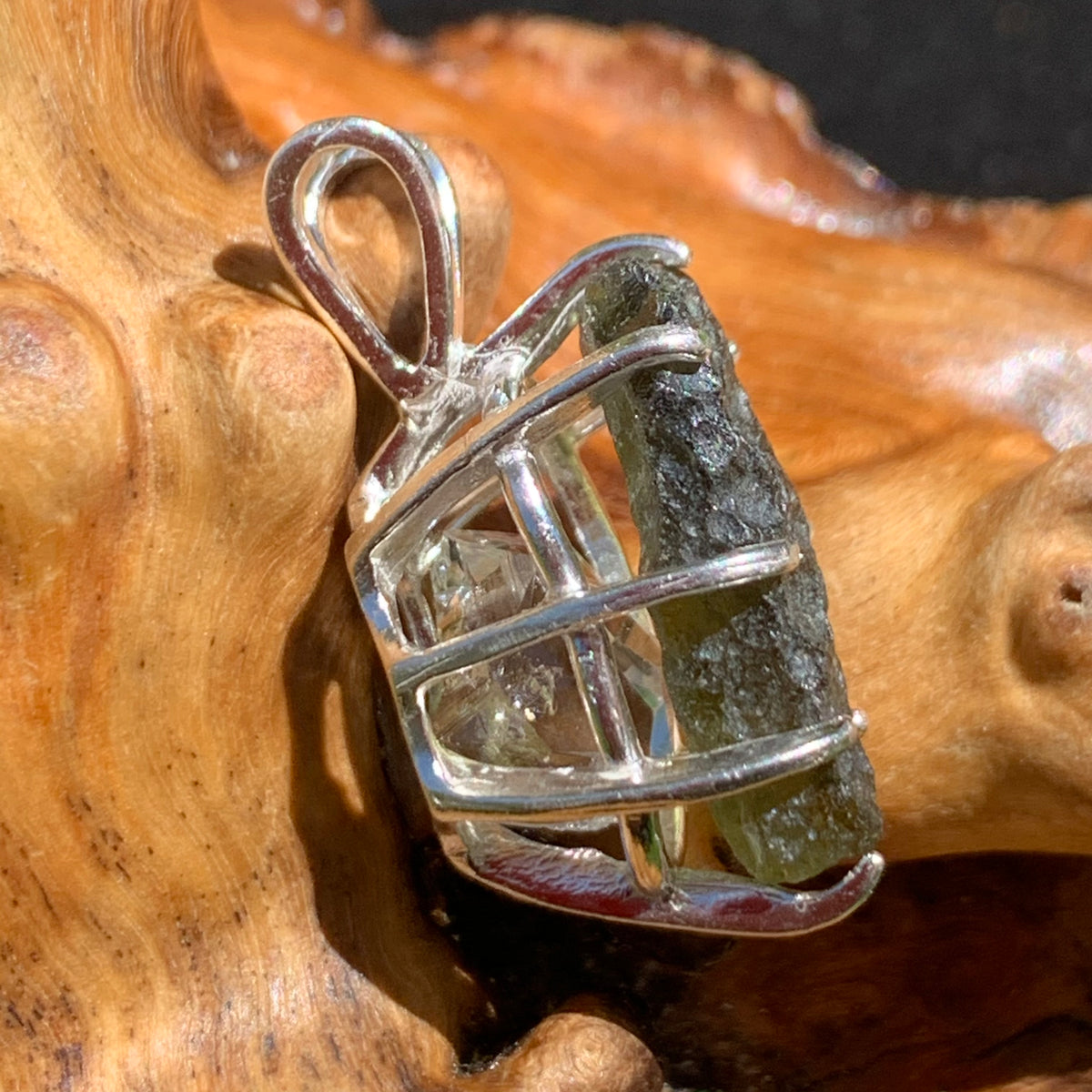 sterling silver moldavite tektite and herkimer diamond basket pendant sitting on driftwood for display