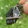 the moldavite herkimer diamond pendant is held out so it can be seen in the light