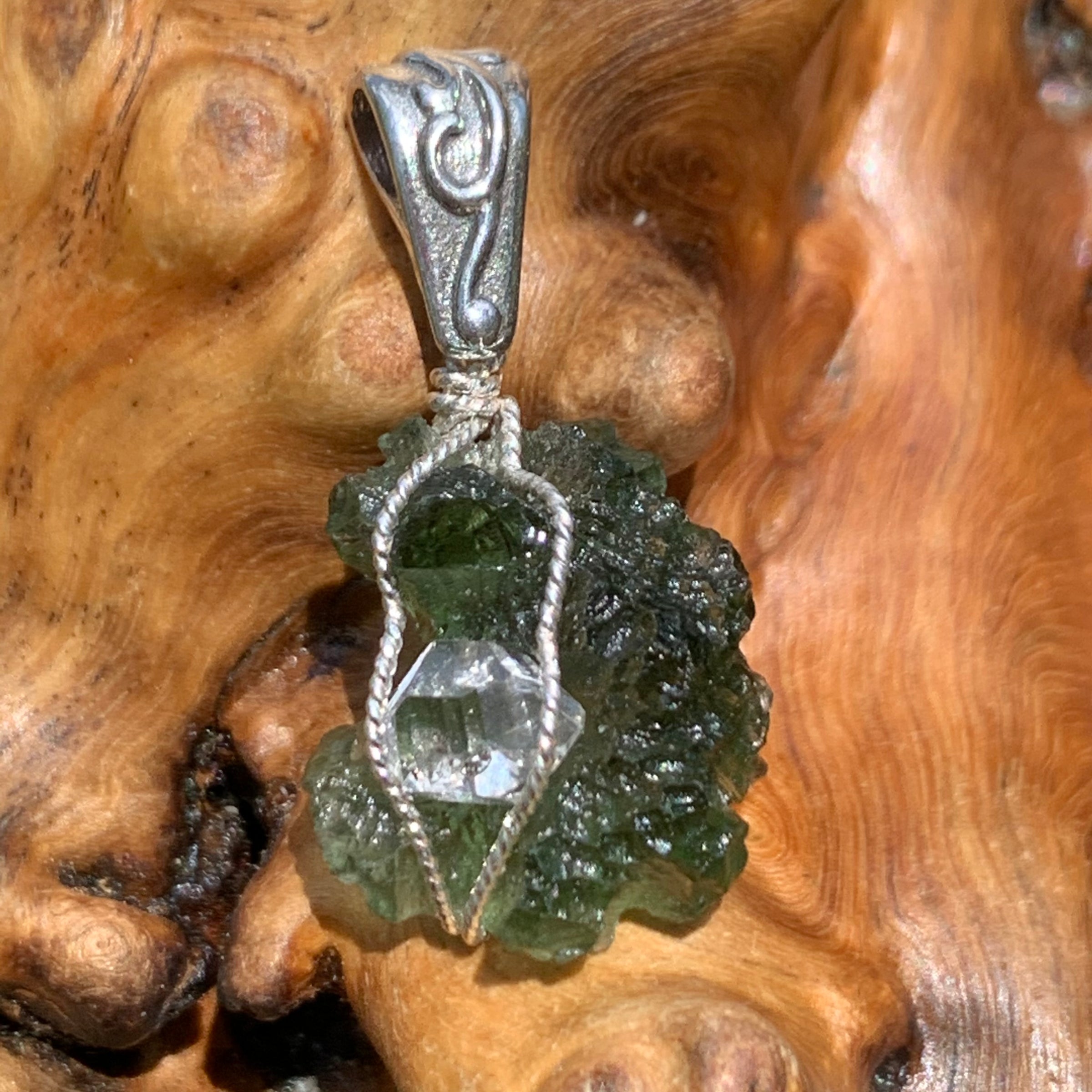 the moldavite herkimer diamond pendant is displayed on driftwood