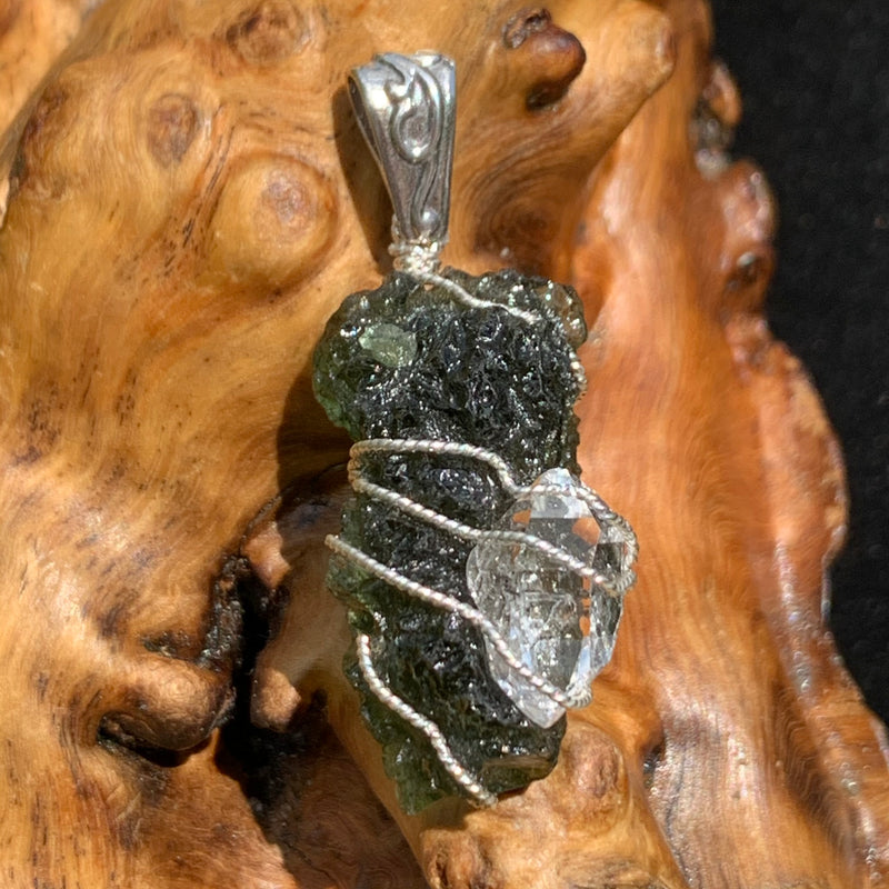 the beautiful moldavite herkimer diamond pendant is displayed on driftwood
