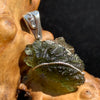 Moldavite pendant wire wrapped in sterling silver sitting on driftwood for display