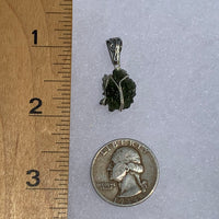 Wire wrapped moldavite pendant next to a ruler and US quarter to show scale