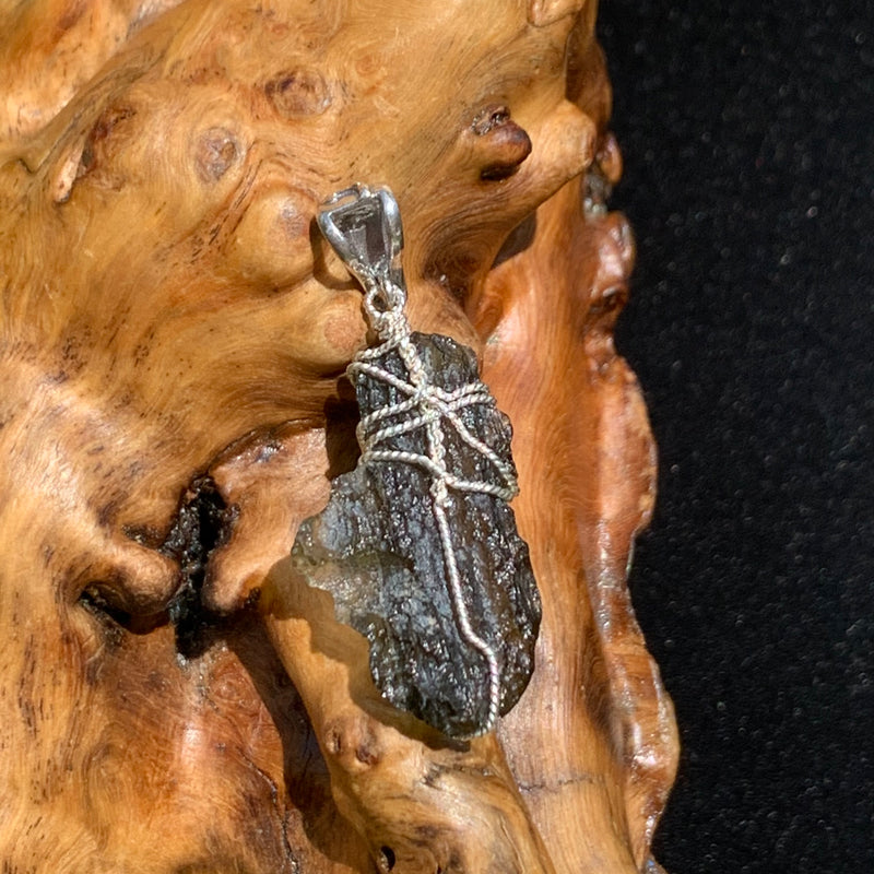 back of Moldavite sterling silver pendant displayed on driftwood