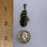 the moldavite pendant sits next to a ruler and US quarter