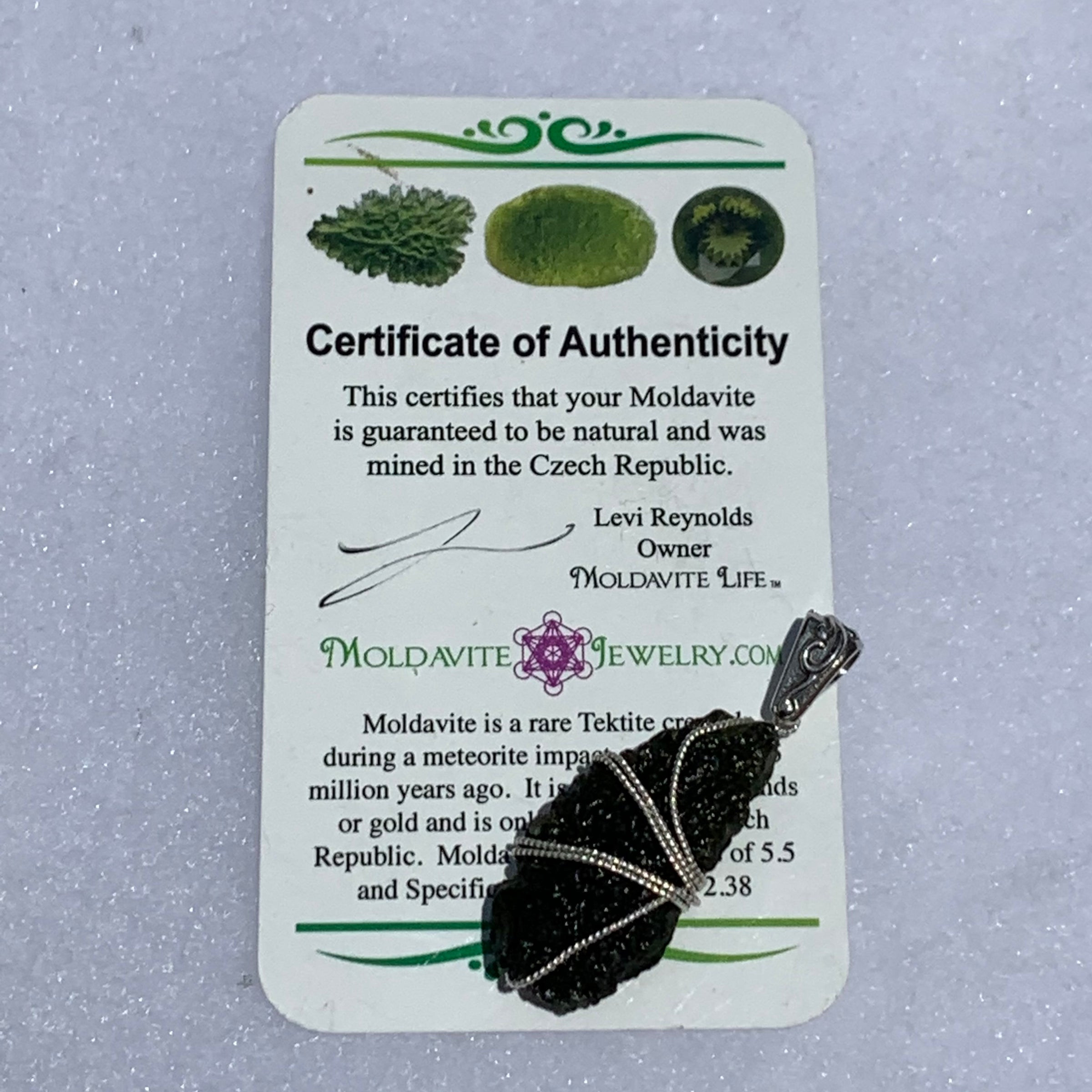 the moldavite pendant sits on the certificate of authenticity