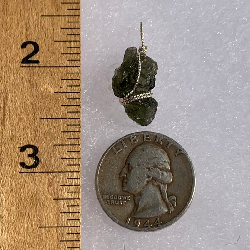 Moldavite sterling silver pendant next to a ruler and quarter