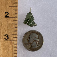 Moldavite sterling silver pendant next to a ruler and quarter