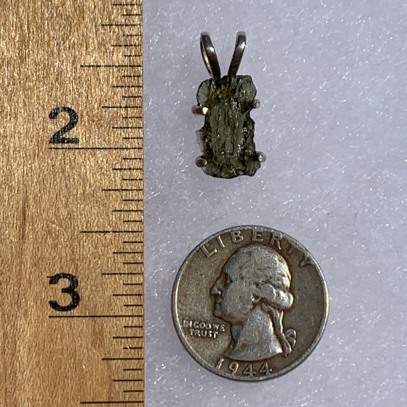 raw moldavite tektite in 4 prong sterling silver basket pendant next to ruler and quarter for scale