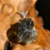 raw moldavite tektite sterling silver basket pendant sitting on driftwood for display