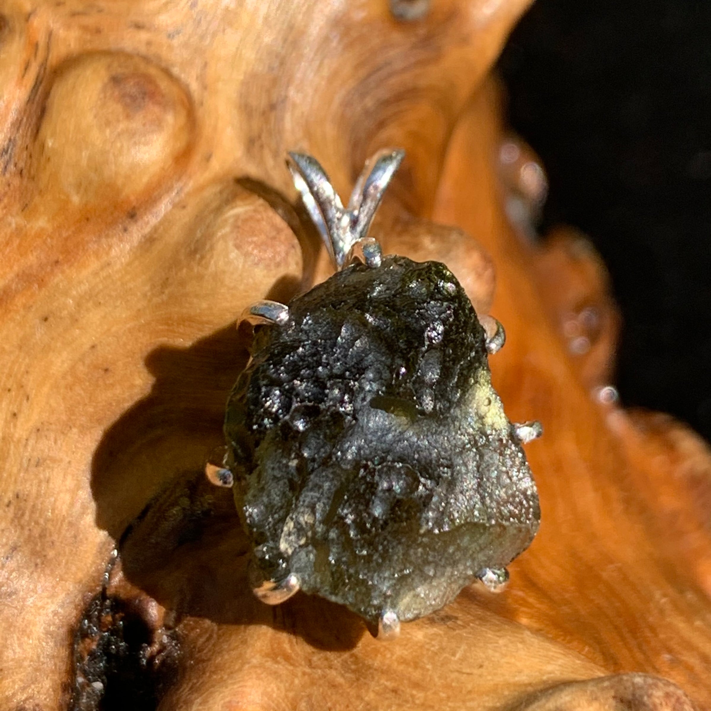 raw moldavite tektite sterling silver basket pendant sitting on driftwood for display