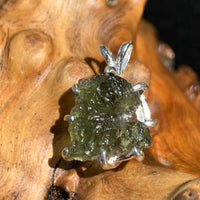 raw moldavite tektite sterling silver basket pendant sitting on driftwood for display