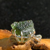 raw moldavite tektite sterling silver basket pendant sitting on driftwood for display