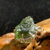 raw moldavite tektite sterling silver basket pendant sitting on driftwood for display