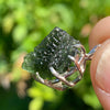 raw moldavite tektite sterling silver basket pendant held up on display to show details