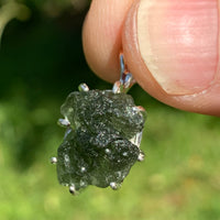 raw moldavite tektite sterling silver basket pendant held up on display to show details