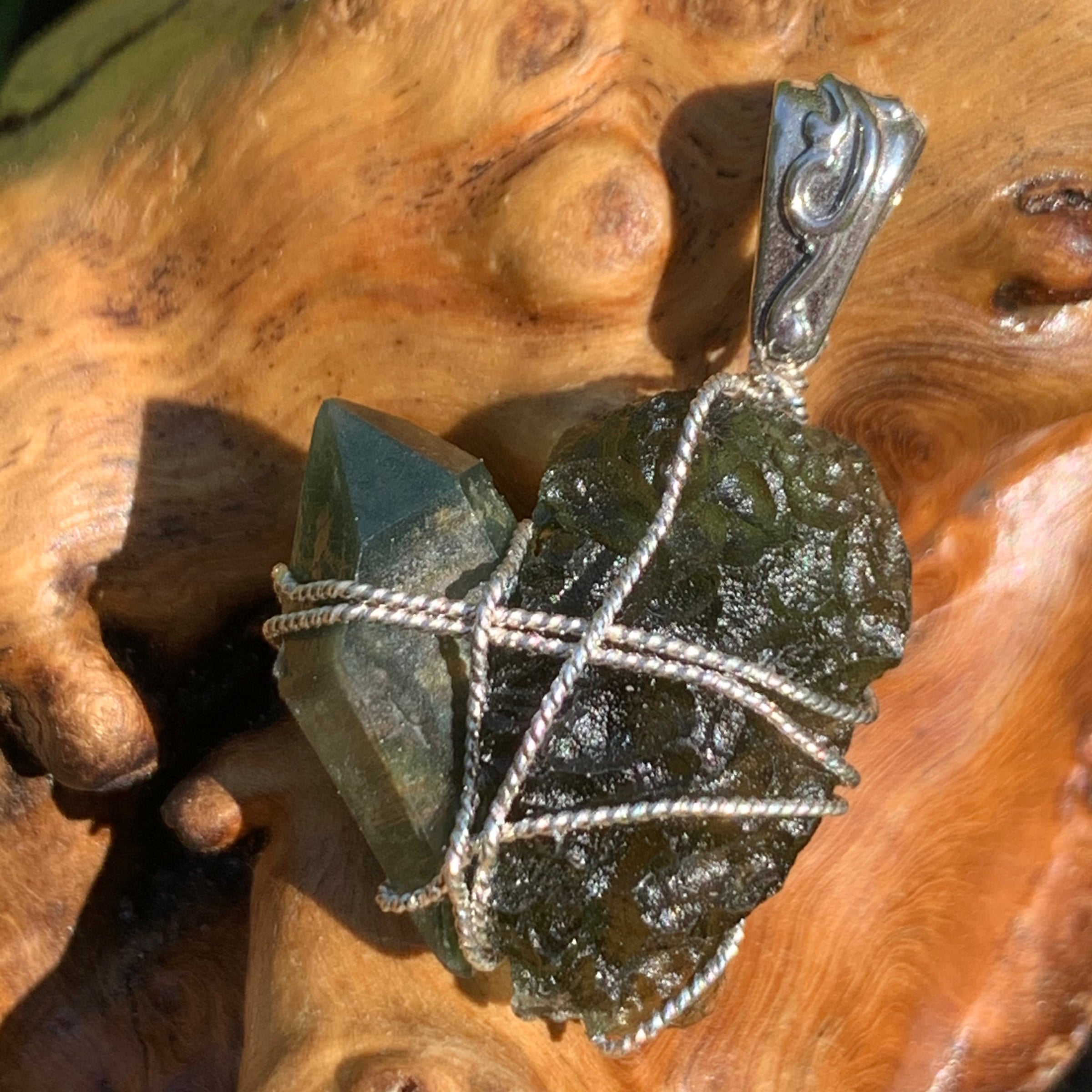 raw moldavite tektite and chlorite quartz crystal sterling silver wire wrapped pendant sitting on driftwood for display