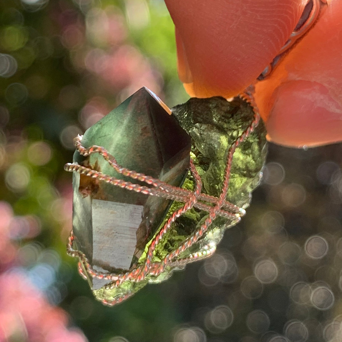 raw moldavite tektite and chlorite quartz crystal sterling silver wire wrapped pendant held up on display to show details