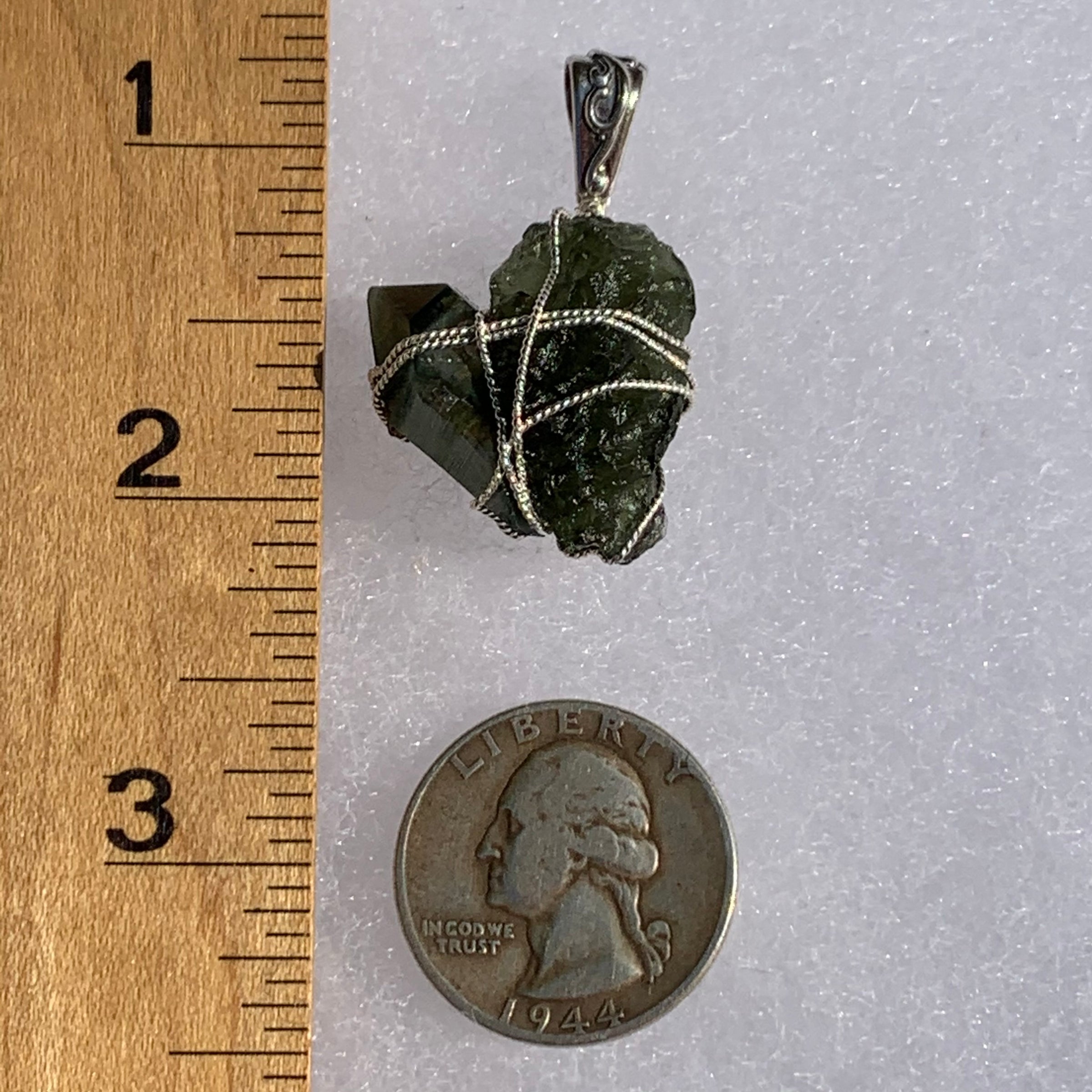 raw moldavite tektite and chlorite quartz crystal sterling silver wire wrapped pendant next to a ruler and US quarter for scale